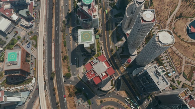 Aerial birds eye overhead top down view of multilane road leading along group of tall buildings in Santa Fe. Tilt down shot. Mexico City, Mexico.