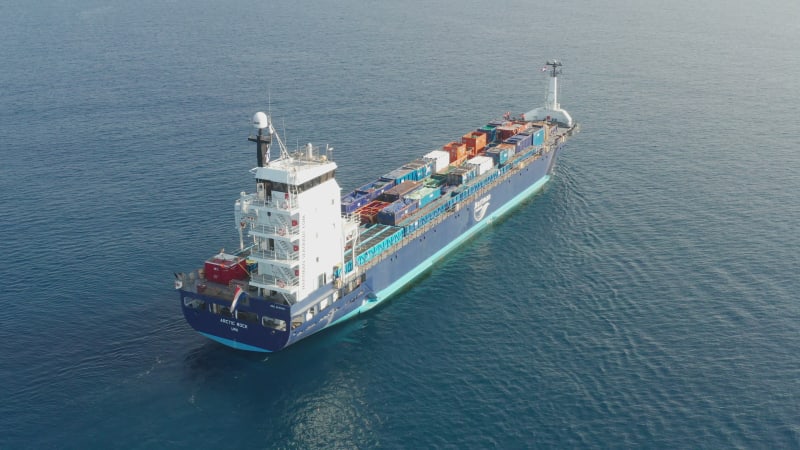 Cargo Ship loaded with colourful Containers and large crates cruising at sea