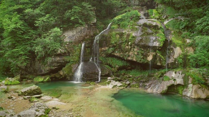 Aerial view of cyclists standing with their bicycles in front of a waterfall.