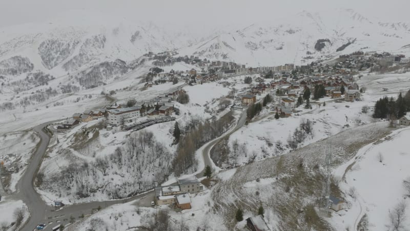 Tilt up pivoting the ski village La Toussiere, France and snow covered mountains during foggy weather. 