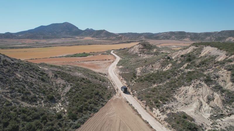 Aerial view of a car driving in a plain valley in Bardenas region in Spain.