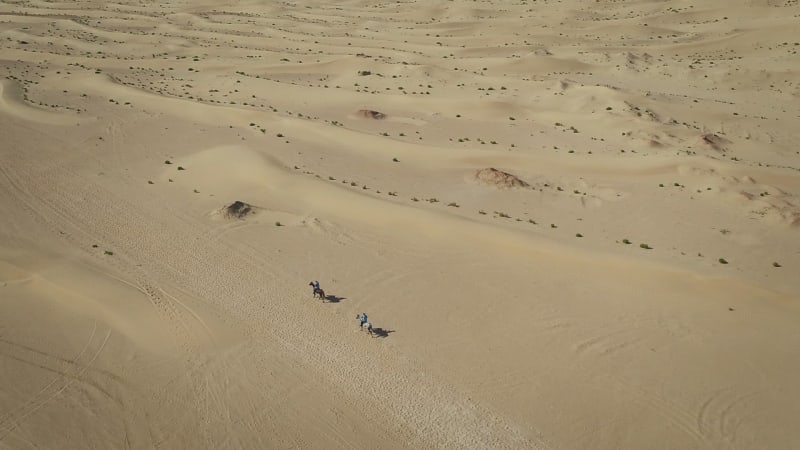 Aerial view of people riding horses in the desert of Al Khatim.