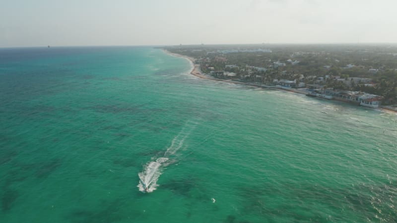 Stunning aerial view with the calm Caribbean Sea and the beaches at Playa del Carmen. Jet ski rider cruising on the calm water