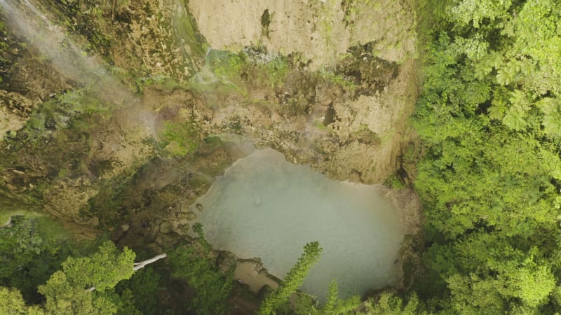 Top down view of waterfall on rocky cliffs with pool at the bottom