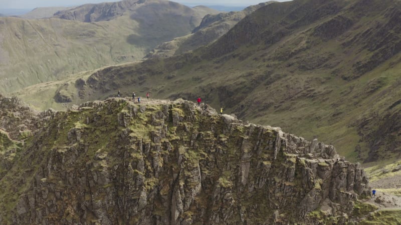 Group of hikers at the mountain summit surrounded by stunning rocky landscape