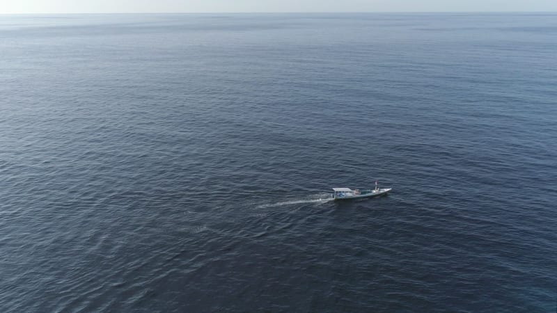 Aerial view of single traditional boat anchored next to Maldives island.