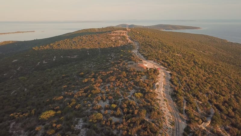 Aerial view of road crossing mountain summit during the sunset.