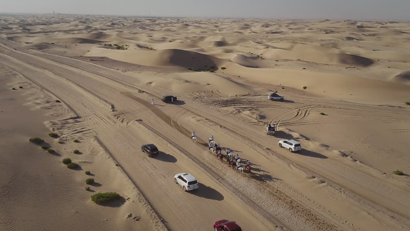 Aerial view of people riding horses in the desert of Al Khatim.