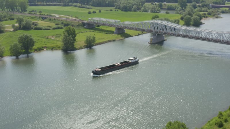 Aerial around the front of a barge sailing up a picturesque Dutch river