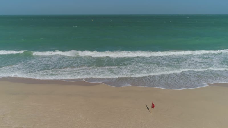 Aerial view of flag waving on beach on bay Dubai.