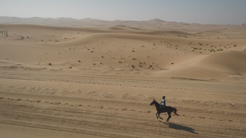 Aerial view of one person riding horse in the desert of Al Khatim.