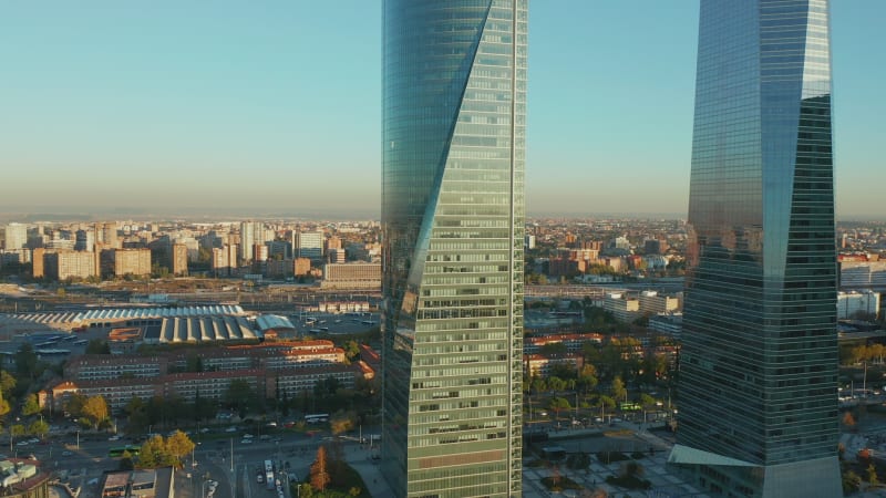 Fly around tall modern office buildings in business hub. Futuristic design of skyscrapers in city. Evening golden hour.