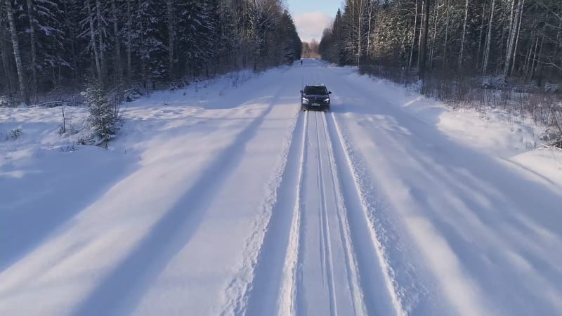 Aerial view of a car reversing in the snowy forest in Estonia