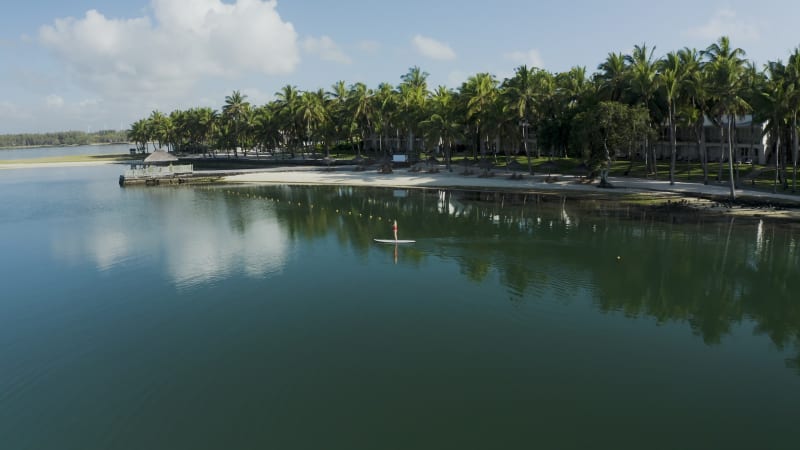 Aerial view of a blonde girl paddling a surfboard, Mauritius.