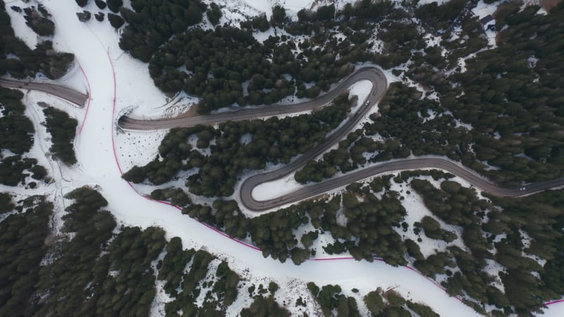 People skiing on a ski track across the alpine road