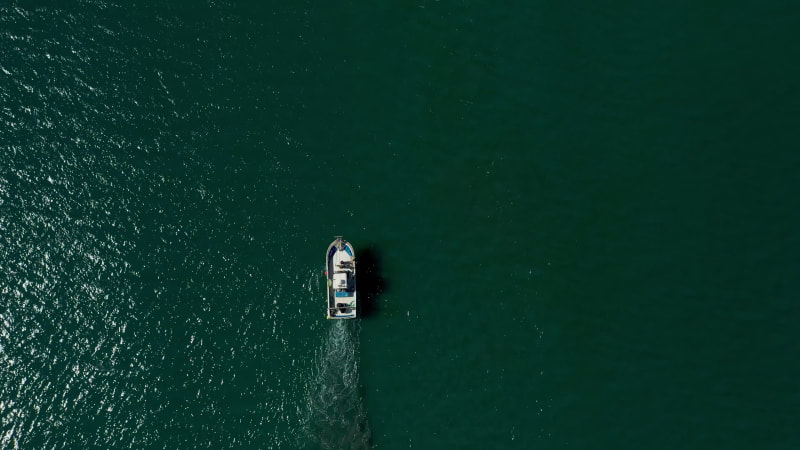 Aerial view of a small fishing boat sailing near Estepona, Malaga, Spain.