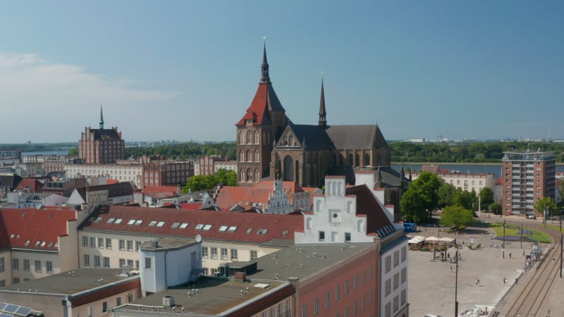 Aerial view of town square with historic colourful gabled houses and Saint Marys church. Wide river estuary in distance