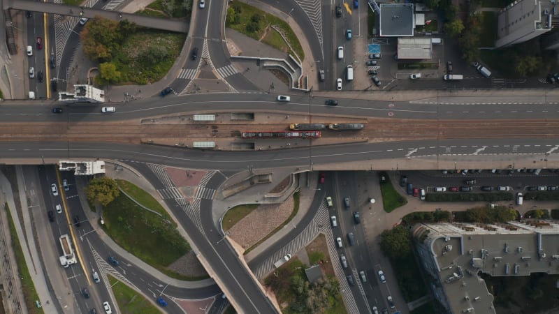 Aerial birds eye overhead top down view of traffic on road intersection on riverbank. Trams stopping at tram stop. Transport in city. Warsaw, Poland