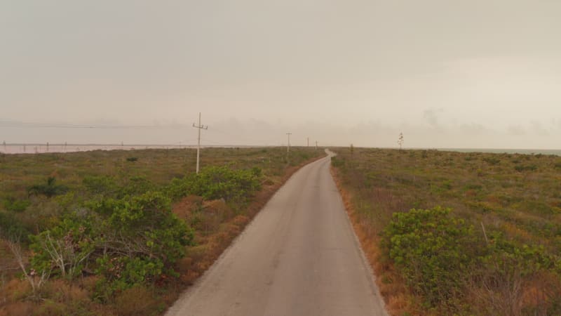 Forwards fly above road leading on narrow stripe of land. Revealing water surface of sea and pink lakes. Las Coloradas, Yucatan, Mexico