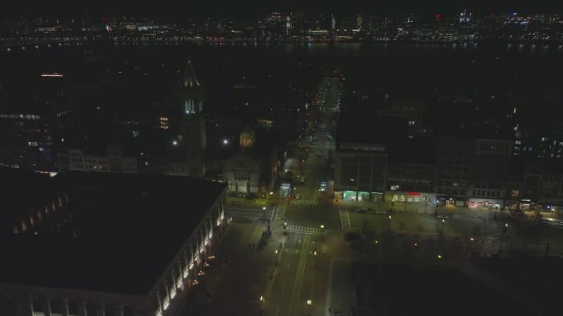 Forwards fly above night city. Tilt down shot of road intersection with crosswalks in urban borough. Boston, USA