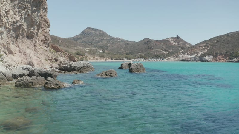 Low flight above Turquoise Blue Ocean Water and Rocky Cliff Coast in Greece