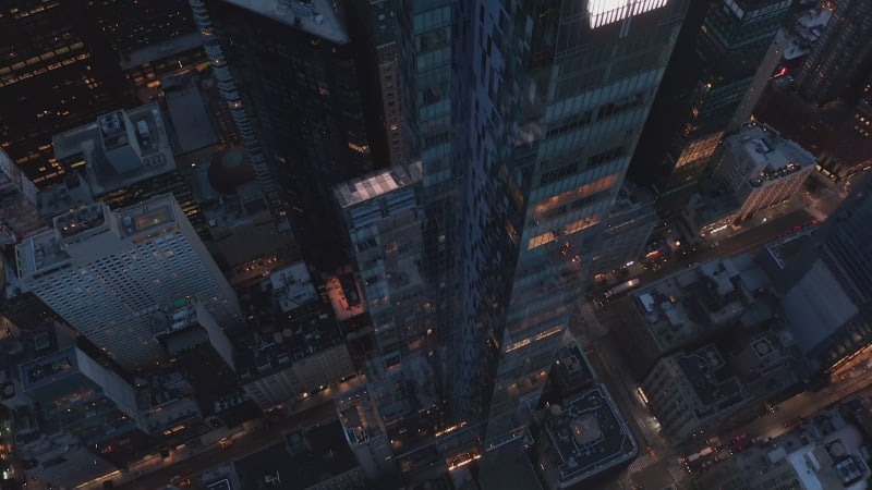 Looking down tall modern Skyscraper in Manhattan with beautiful City lights at Night with traffic on Street and Office Buildings, Aerial Drone Shot wide angle view