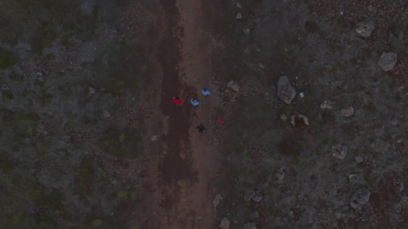 Overhead view birds eye of four people friends walking rocky desert in iceland highlands. Top down drone view of tourist walking pathway exploring wilderness