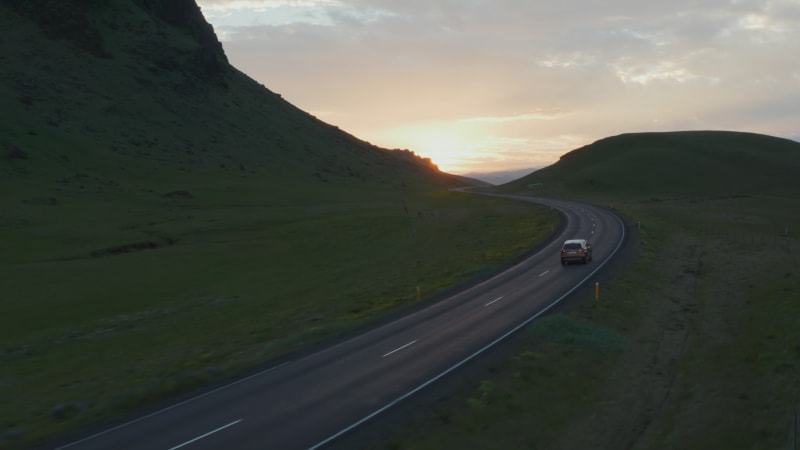 Drone view of highway car peacefully driving in golden hour in evening. Birds eye view car fast driving on ring road, the most important highway in Iceland