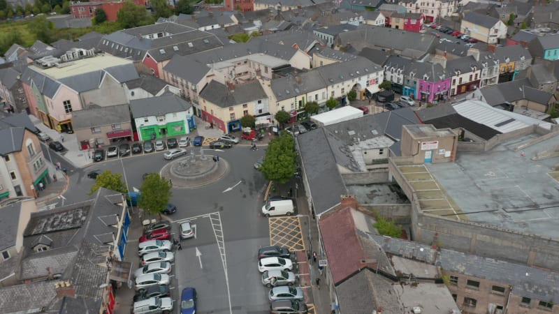 Circular shot of town centre. Square with roundabout and parked cars. Shopping streets around. Ennis, Ireland