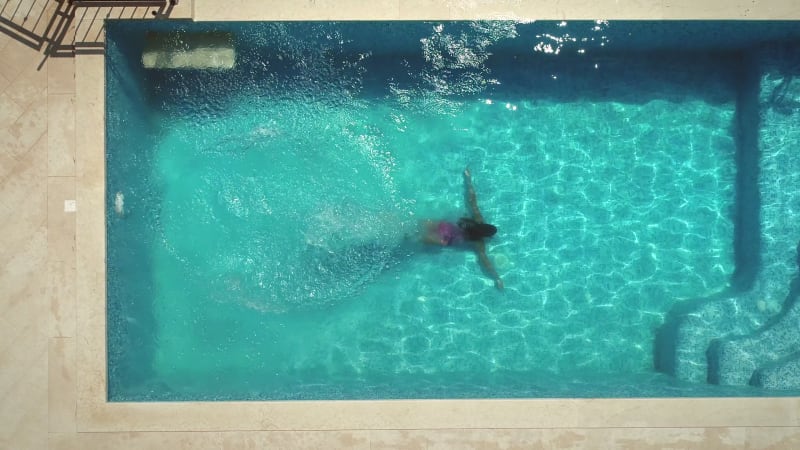 Aerial view of young woman diving into swimming pool.