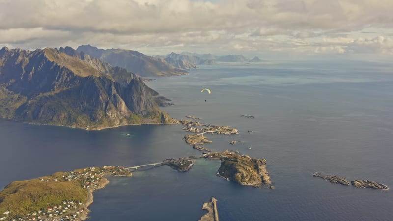 Paraglider moving over seaside town in Reine, Norway.