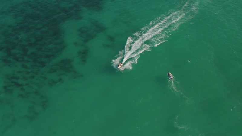 Young couple jetskiing at high speed on the green Caribbean Sea. Aerial Birds Eye Overhead Top Down View