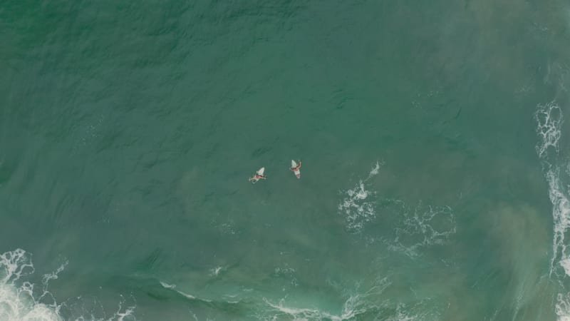 Top down view of two surfers preparing to surf on the waves.