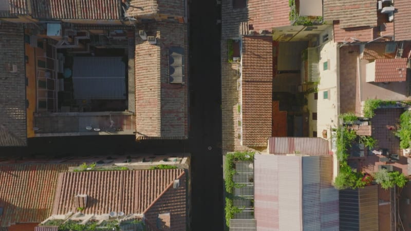 Fly above residential houses in urban borough. Top down panning footage of narrow streets and buildings with balconies and terraces. Rome, Italy