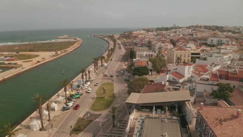 Establishing aerial drone view of Lagos city by sea, Algarve, Portugal, downtown cityscape, tilt down to birds eye overhead top down view of Gil Eanes square, day