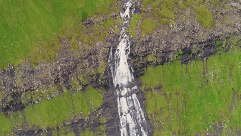 Aerial view of breathtaking waterfall crossing rock mountain.