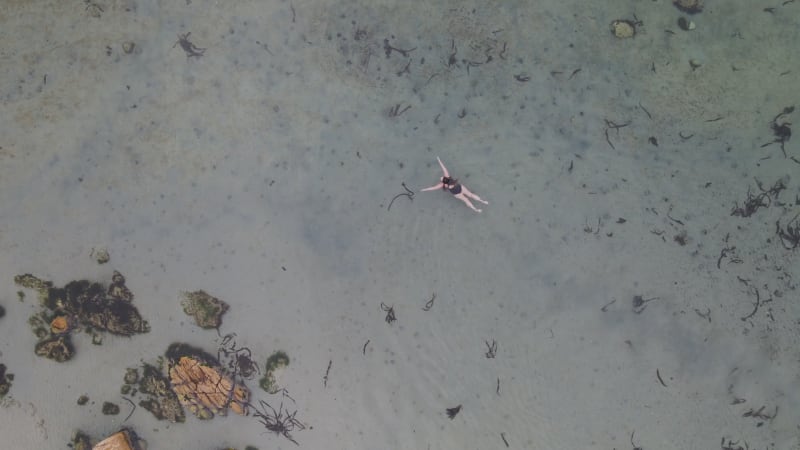 Aerial view of woman swimming in Glencairn pool, Cape Town, South Africa.