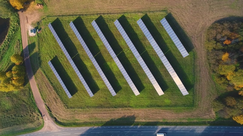 Aerial view of above solar panel rows during strong sunlight.