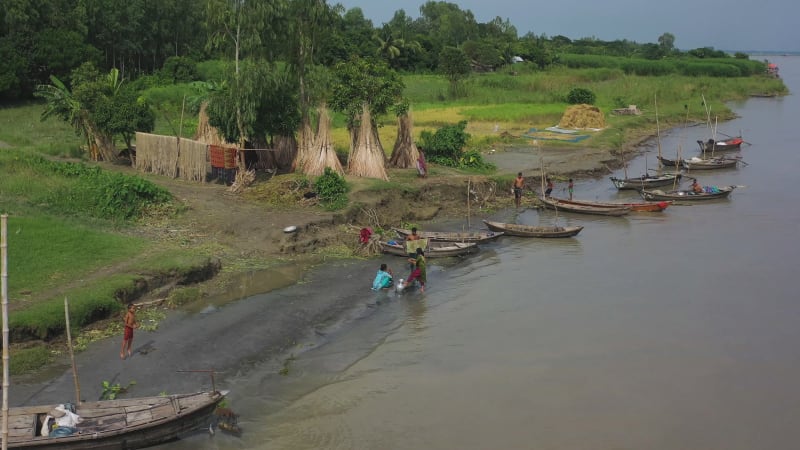 Aerial view of people working along the river on wooden boats.