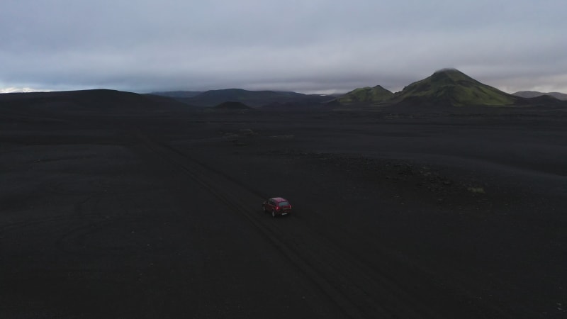 Aerial view of a car driving along a valley with volcanic soil, Iceland.