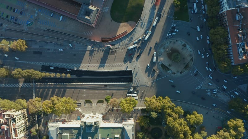 Aerial birds eye overhead top down view of vehicles driving in city, passing through large roundabout. Rush hour on crossroads.