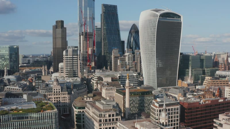 Forwards ascending fly above city. Group of modern tall office buildings in business hub. Iconic The Walkie Talkie skyscraper with sky garden on top. London, UK