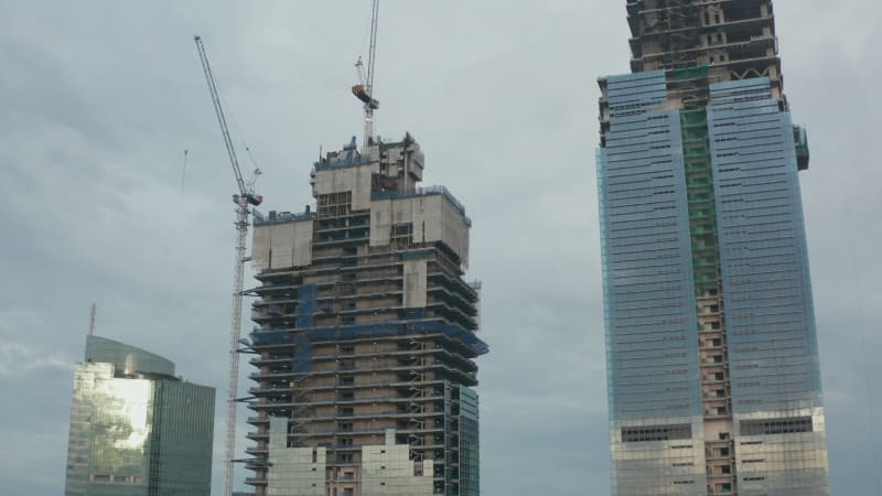 Aerial pedestal shot of a skyscraper tower building under construction in Jakarta, Indonesia on a cloudy day