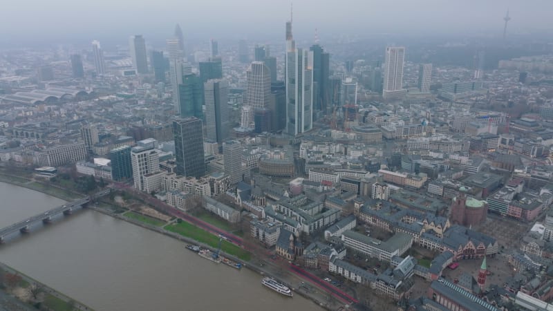 Aerial panoramic footage of city with high rise buildings in business hub. Hazy view of large town. Wide river calmly flowing. Frankfurt am Main, Germany