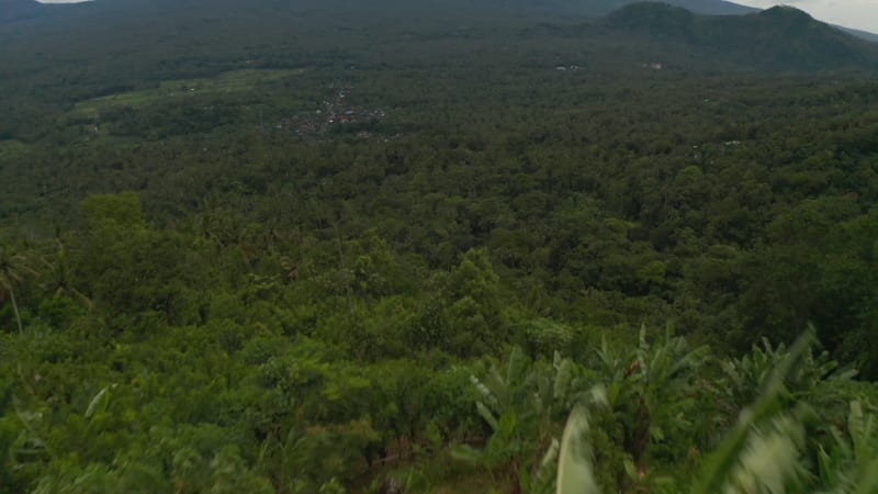 Reveal of Mount Agung in Bali above tropical rainforest. Large isolated mountain peak rising above the jungle in Indonesia