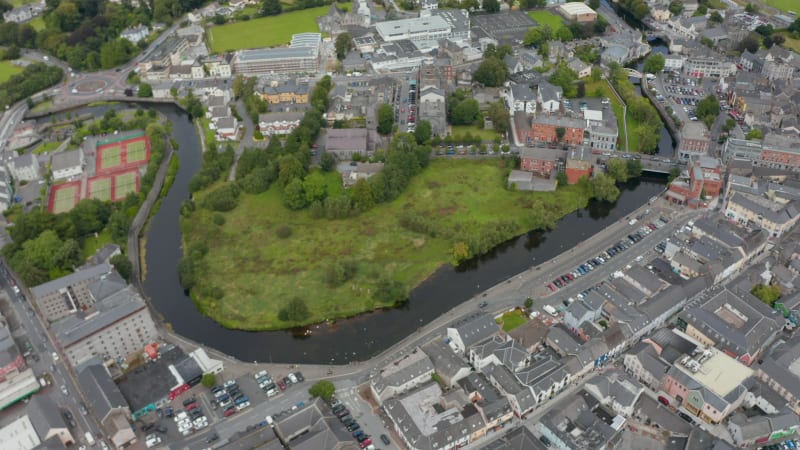 High angle footage of river winding through town. Aerial panoramic shot of city from height. Ennis, Ireland