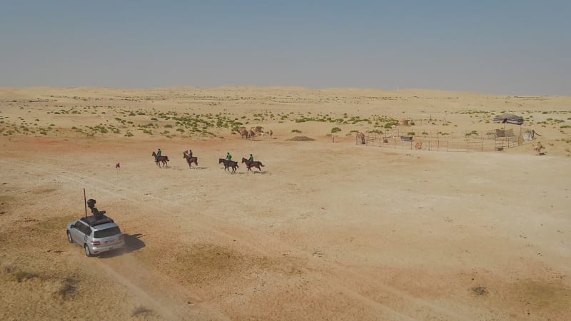 Aerial view of people riding horses in the desert of Al Khatim.