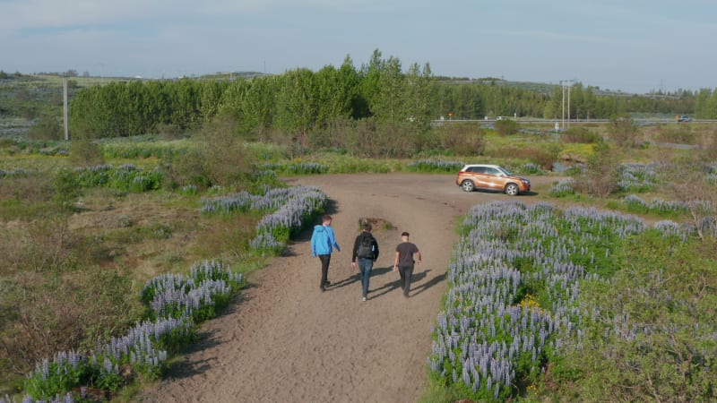 Aerial view birds eye three young men walking away talking together. Drone view group of friends behind view conversation walking car. Tourist leaving landmark ready for traveling