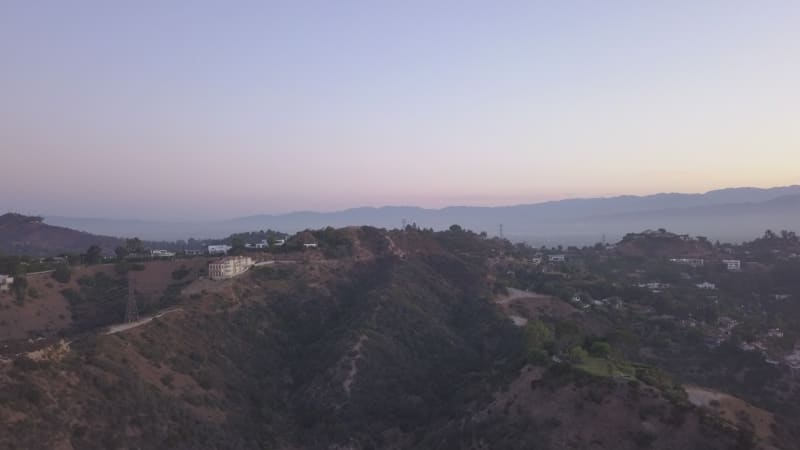 AERIAL: Over Hollywood Hills at Sunrise with view on hills and the valley in Los Angeles view