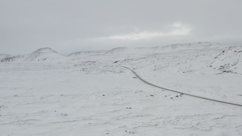 Over Snow White Landscape with Road, Mountain in Iceland Winter, Snowing, Cold, Arctic